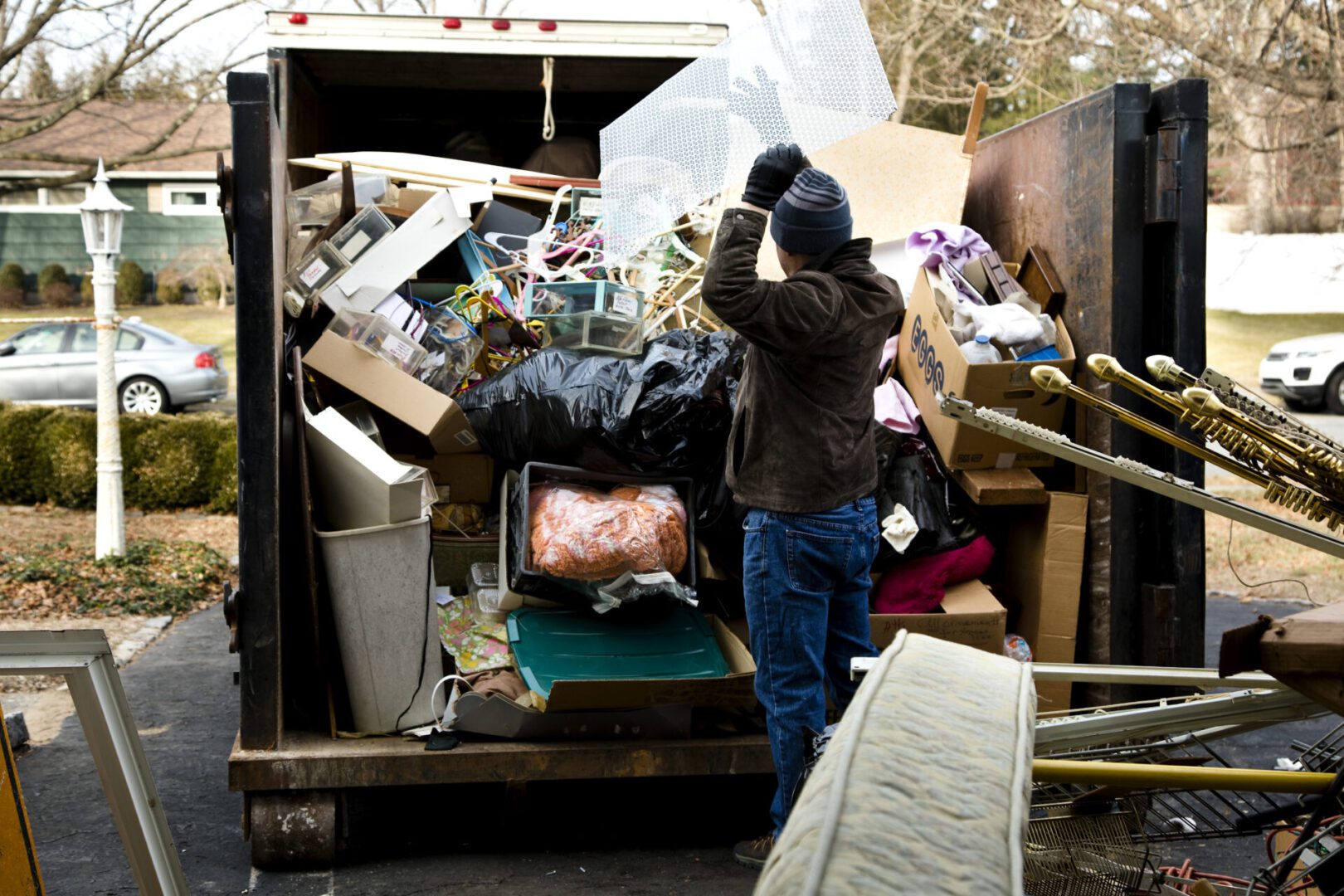 Person loading a dumpster with various items.