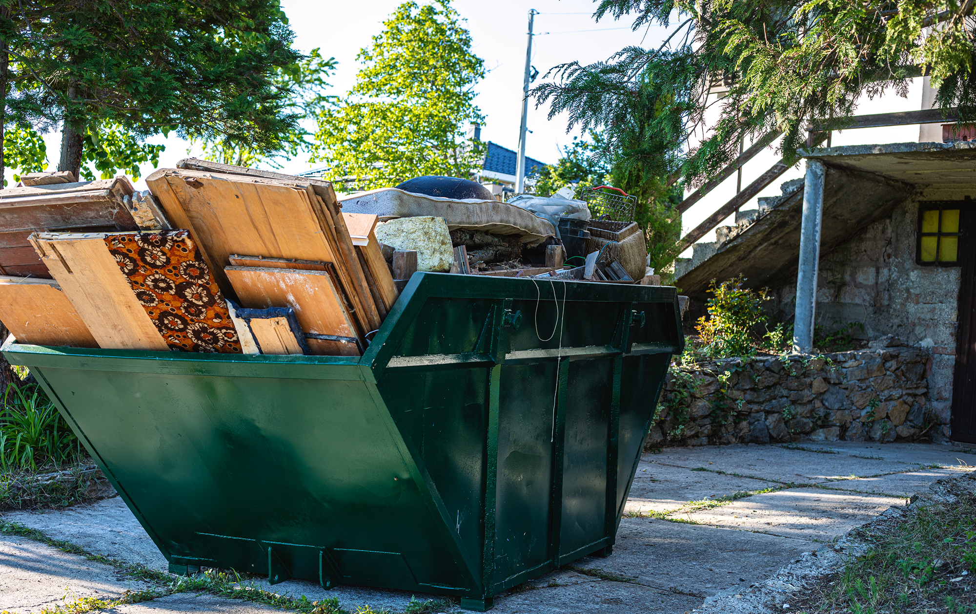 Green dumpster filled with construction debris.