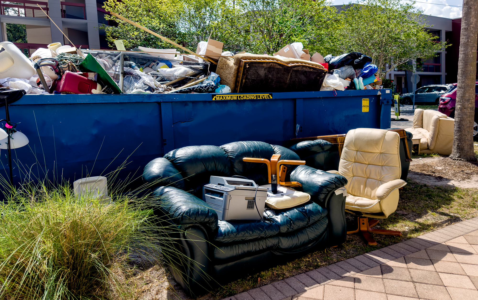 Discarded furniture and electronics by dumpster.